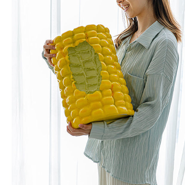 A woman is holding a corn cob stool which looks like a bite has been taken out of it.