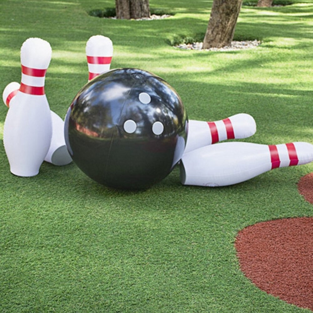 A giant inflatable outdoor bowling set. It is set up outdoors on a lawn and shows the bowling ball having knocked over 3 of the 6 pins.