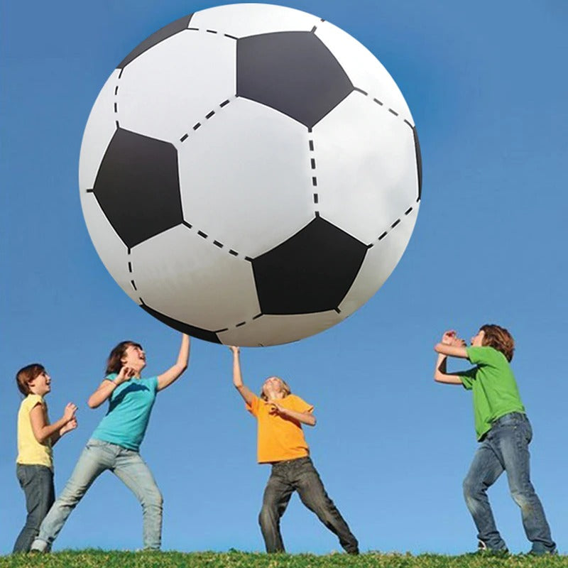 Children playing outdoors with an enormous inflatable soccer ball