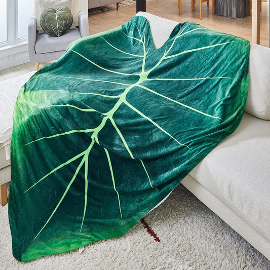 A giant green leaf shaped blanket draped over a beige lounge.