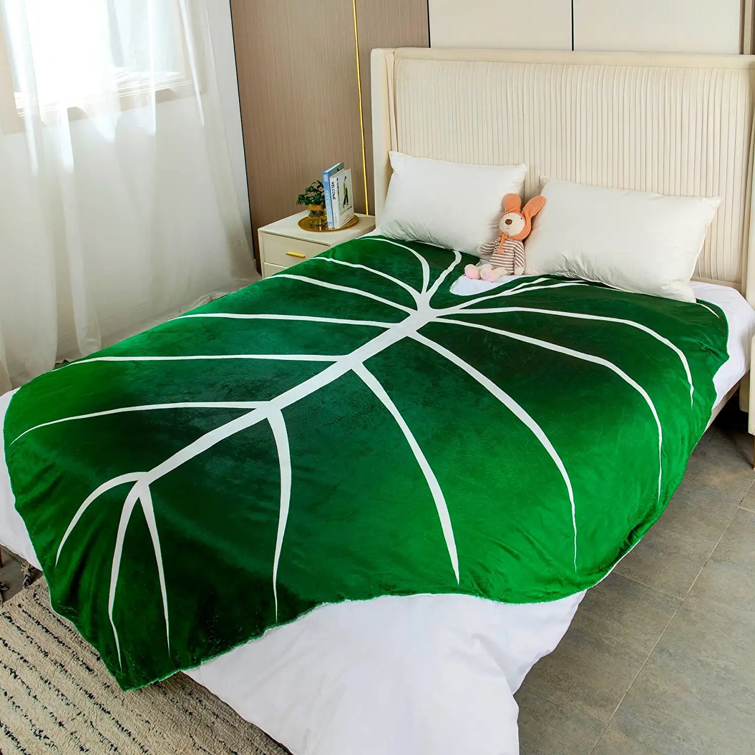 An oversized giant green blanket with white veins resting on a bed.