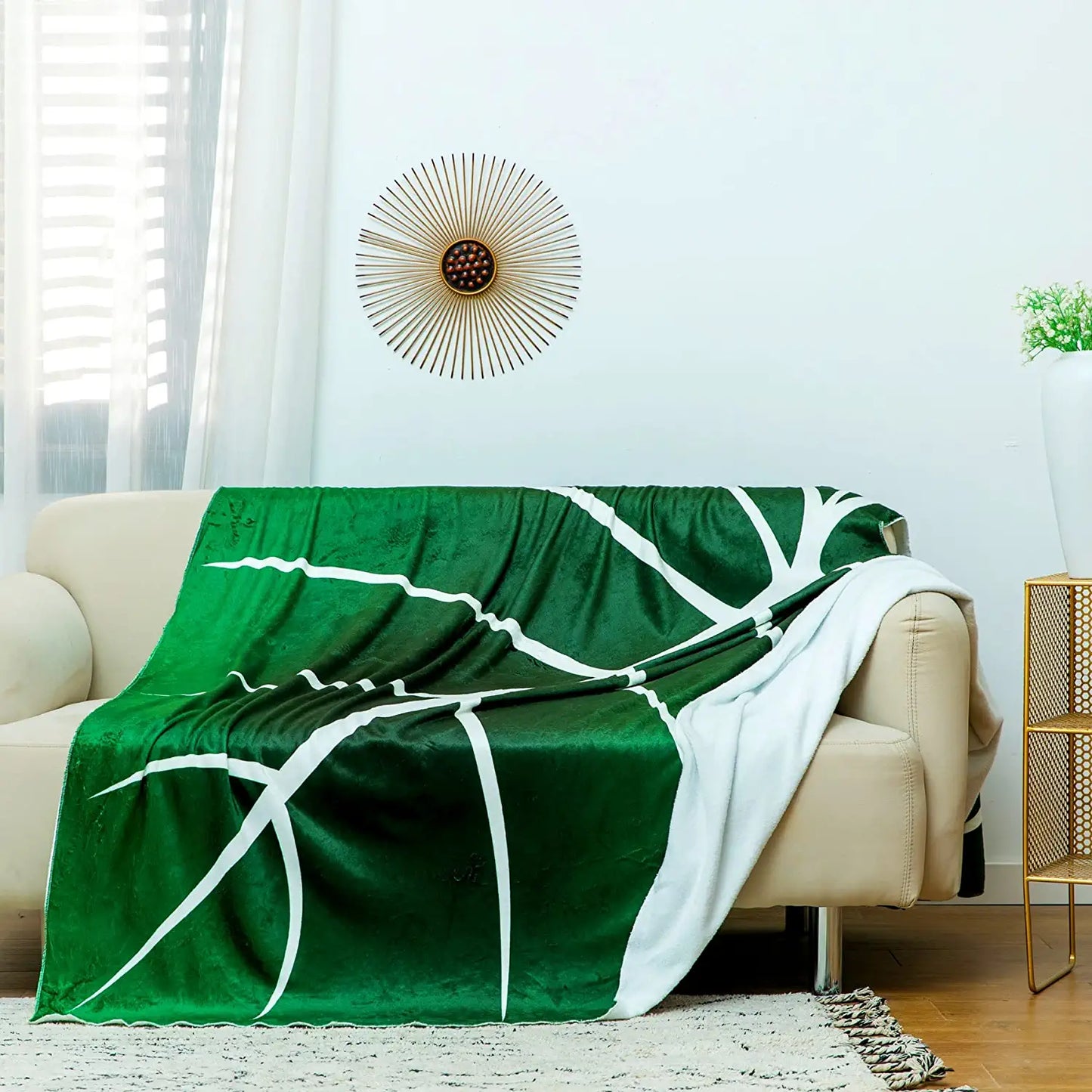 A huge green and white leaf shaped blanket draped over a lounge.