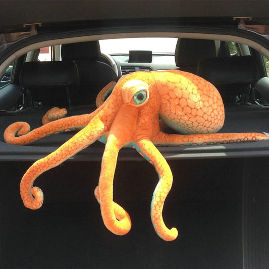 A giant orange octopus plush toy sitting on the rear end of a car