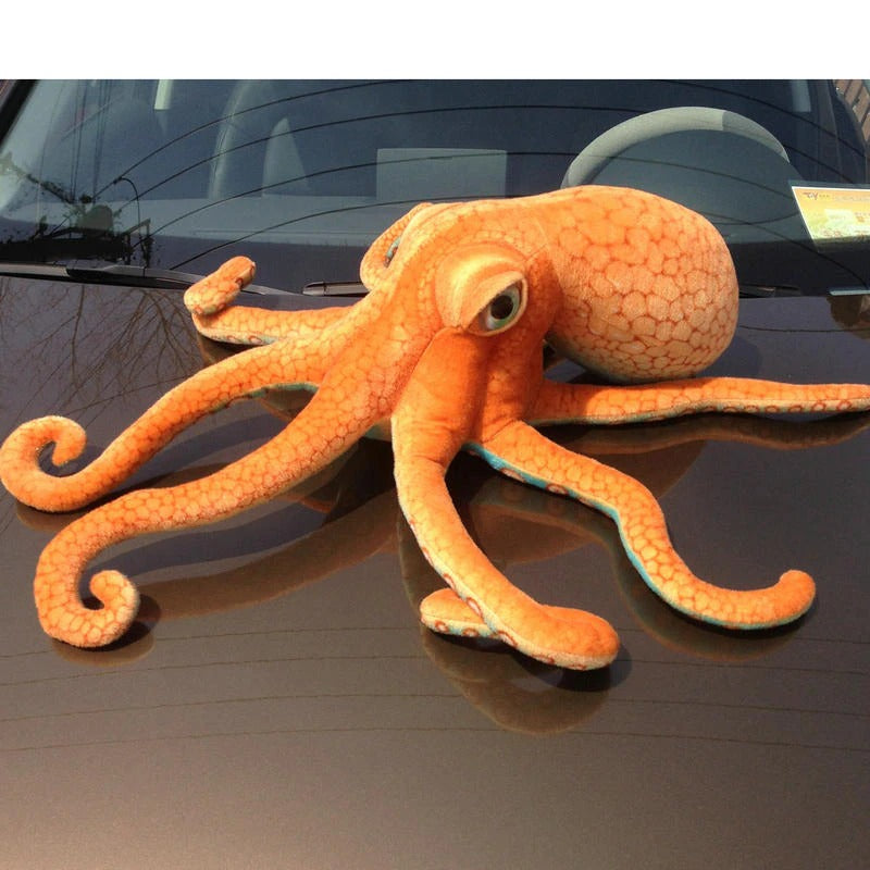 A giant orange octopus plush toy on the hood of a cat