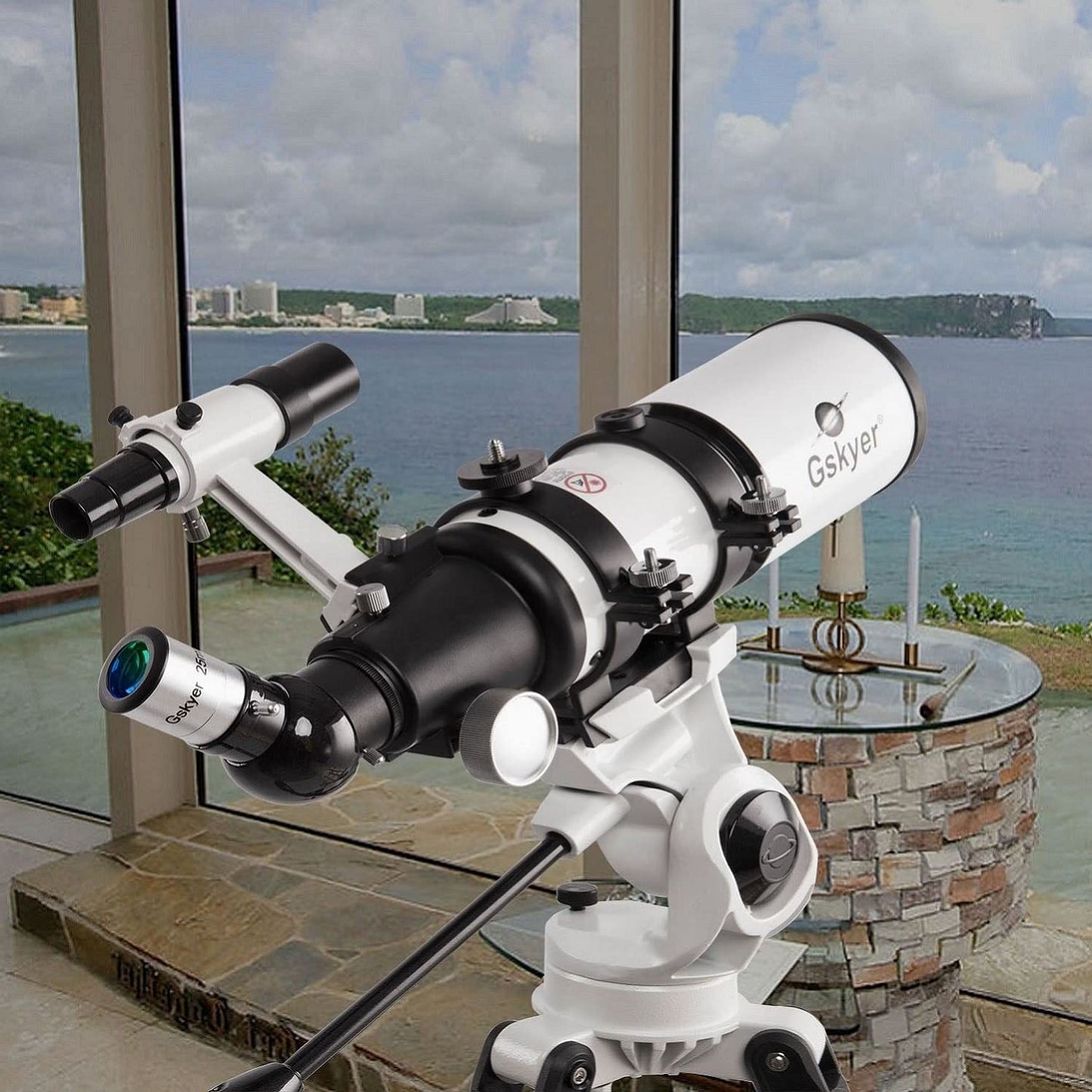 A Gskyer 80mm refractor telescope is inside a room pointing outwards towards the ocean.