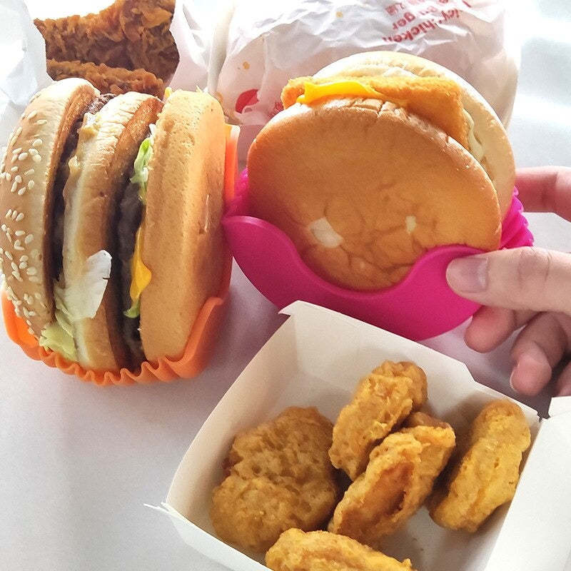 Two hamburger holders being used to hold burgers along with a box of nuggets next to the burger holders.
