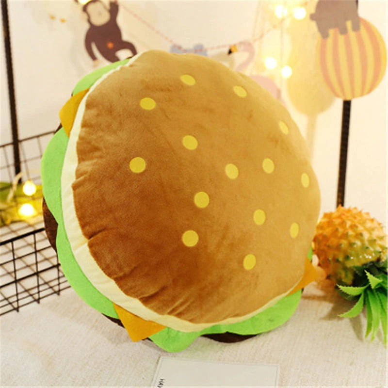 A pillow which is shaped exactly like a hamburger with a sesame bun, lettuce, cheese and a beef patty.