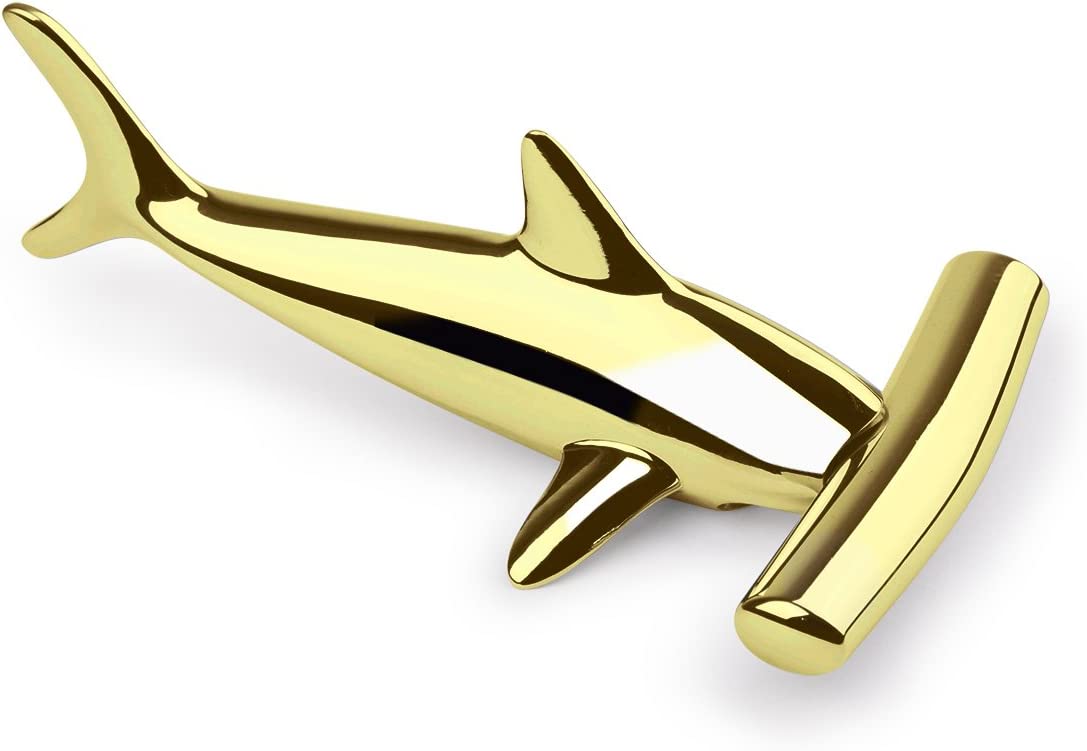 A close-up view of a brass colored bottle opener and corkscrew shaped like a hammerhead shark.