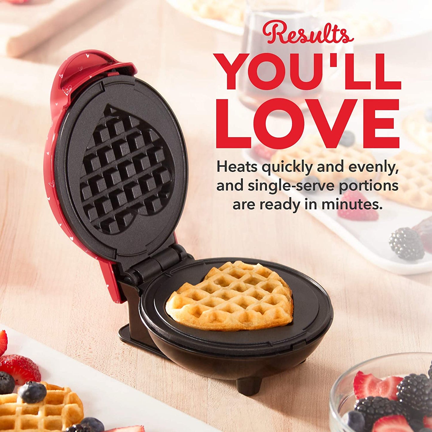 A red heart shaped waffle maker machine with a cooked waffle inside the machine. The headline reads, 'Results you'll love, heats quickly and evenly and single-serve portions are ready in minutes.'
