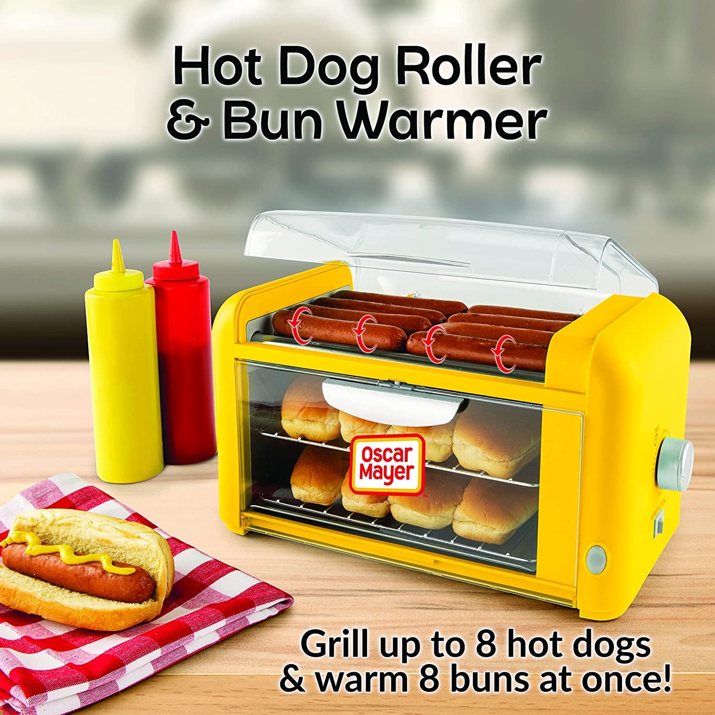 A hot dog roller and bun warmer filled with food. Near by are two bottles of sauce and a cooked hot dog ready to eat.