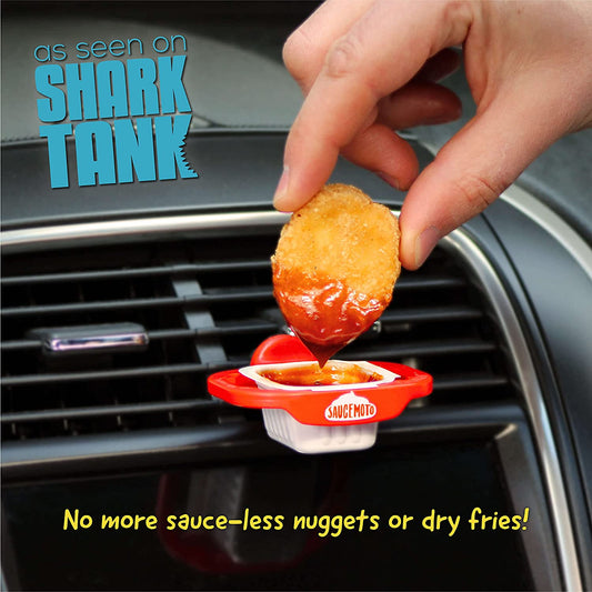 An in car sauce holder attached to the vent of a car. A hand is dipping a chicken nugget into the sauce which is in the tray.