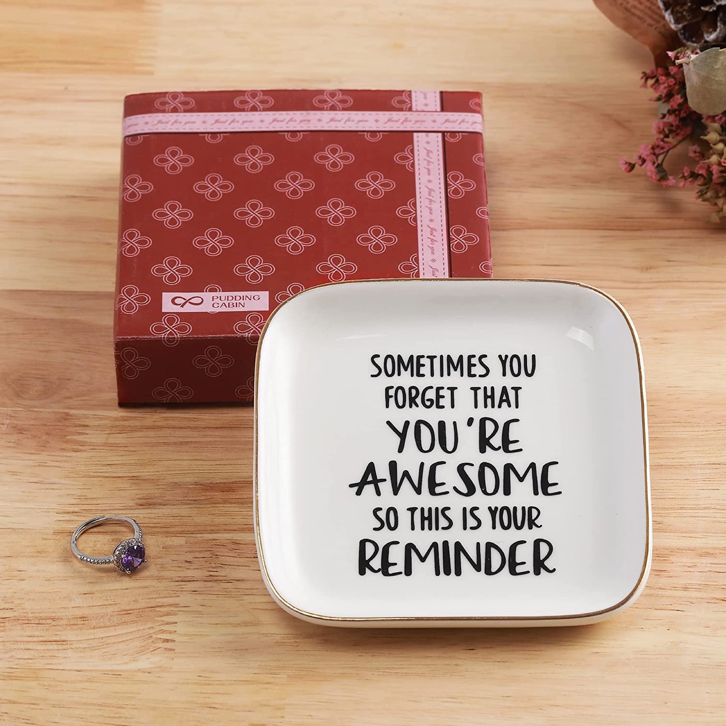 A printed quote on a white ring dish. The quote says, "Sometimes you forget that you're awesome, so this is your reminder".