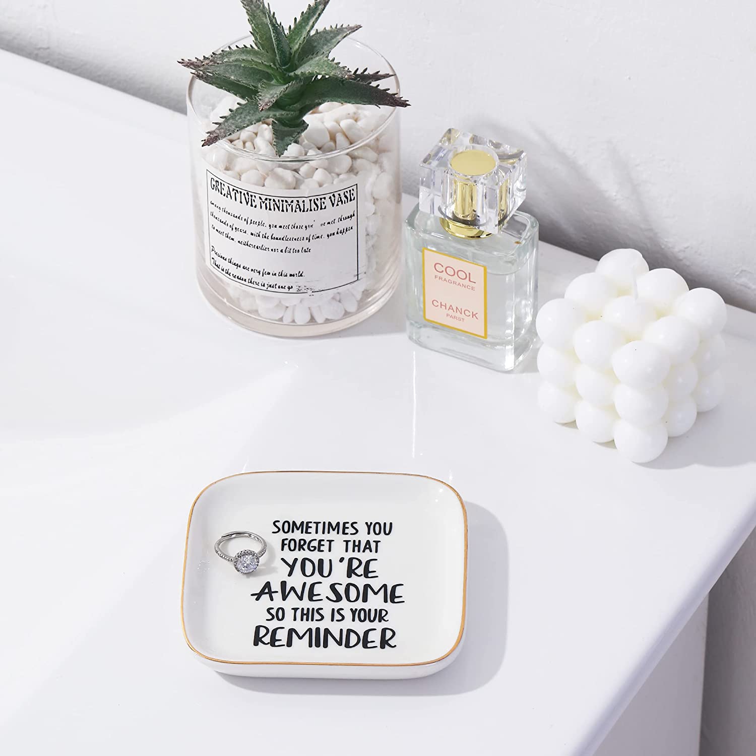 A ring dish on a white table. The ring dish has a quote which says, "Sometimes you forget that you're awesome, so this is your reminder".