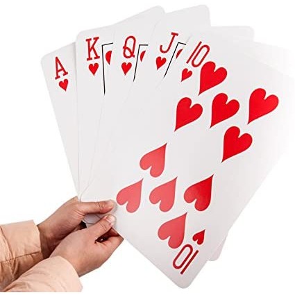 A pair of hands holding 5 jumbo sized playing cards which are Ace, King, Queen, Jack and a 10 of hearts.