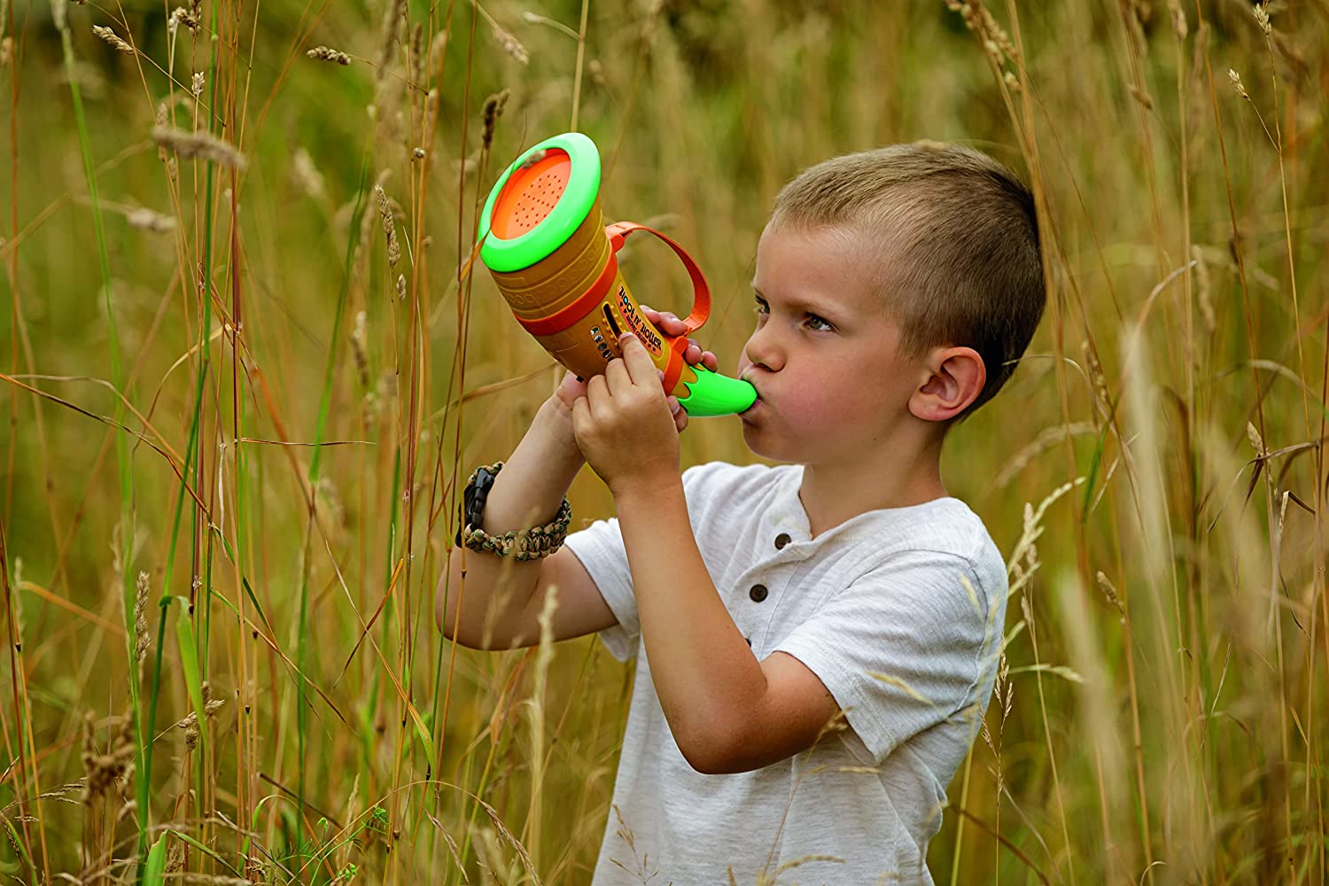 A boy is outdoors using a hoot n' holler animal caller which makes various different animal sounds.