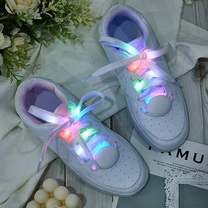 A pair of white sneakers featuring LED light-up shoe laces which are multi-colored.