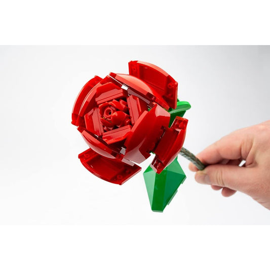 A person is holding a red rose with green leaves and a stem built entirely from Lego.