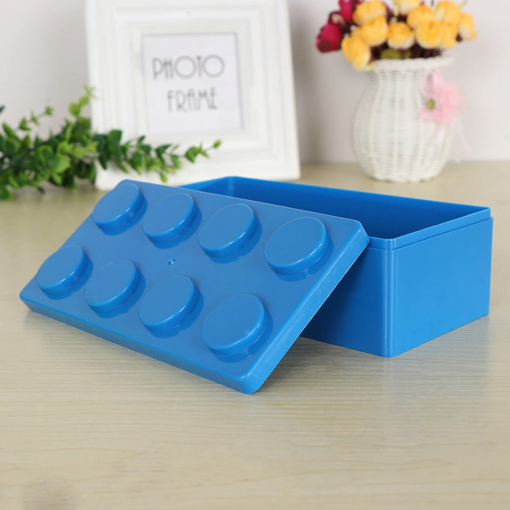 A rectangular shaped blue storage box which looks like a supersized version on a Lego block. The Lego storage box is empty with the lid tilted against it.