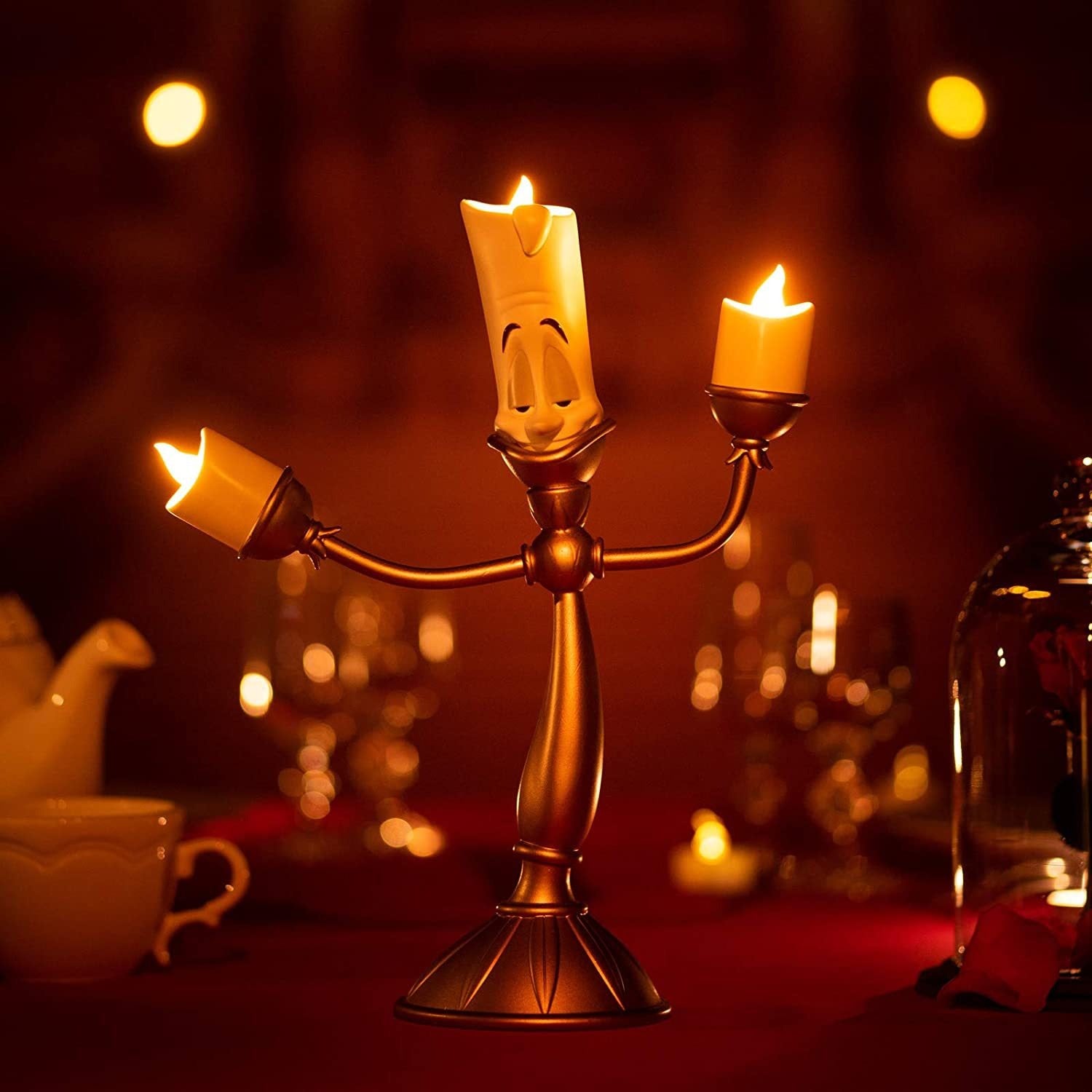 A gold candlestick which looks exactly like Lumiere from Beauty and the Beast. He is holding 2 lit LED candles and has one on his head and appears to be dancing.