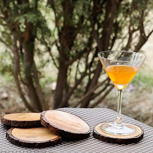 Four wooden coasters outside on a table. A cocktail drink is sitting on one of the coasters.