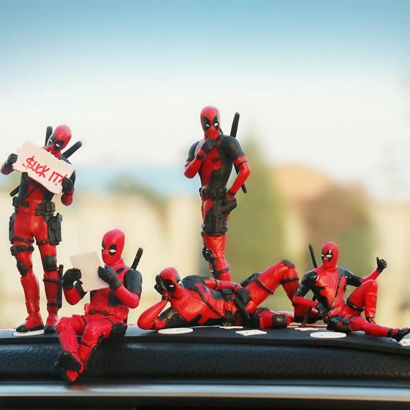 Five Marvel Deadpool action figures posed in different positions sitting on the inside of a car dashboard.