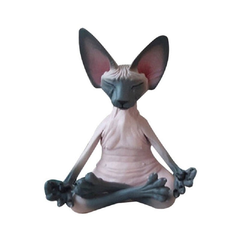 A solitary meditating Sphynx toy cat sitting in a yoga pose with its legs crossed and fingers pinched as if it is meditating. The cat is colored pink and grey.