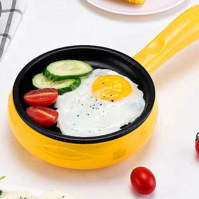 A yellow multi function egg cooker with a fried egg, small tomatos and cucumber in it.