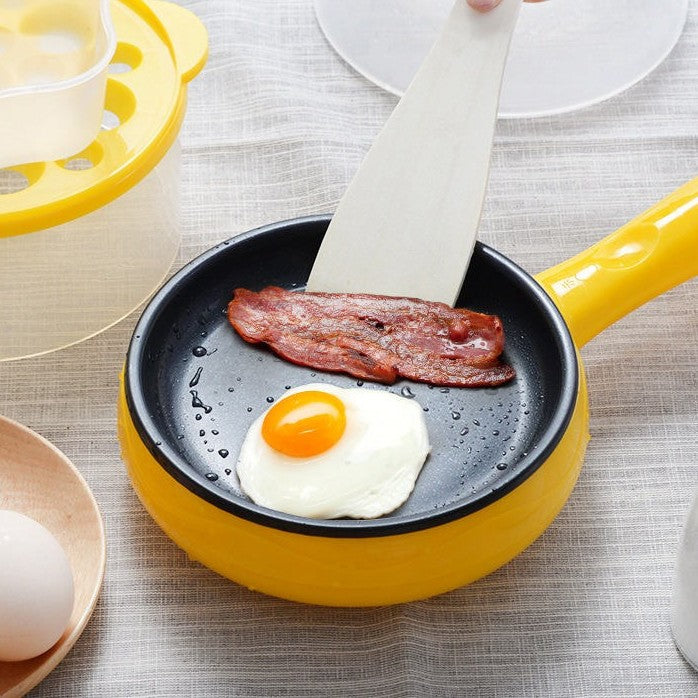 A yellow egg cooker with a fried egg and slice of bacon in it.