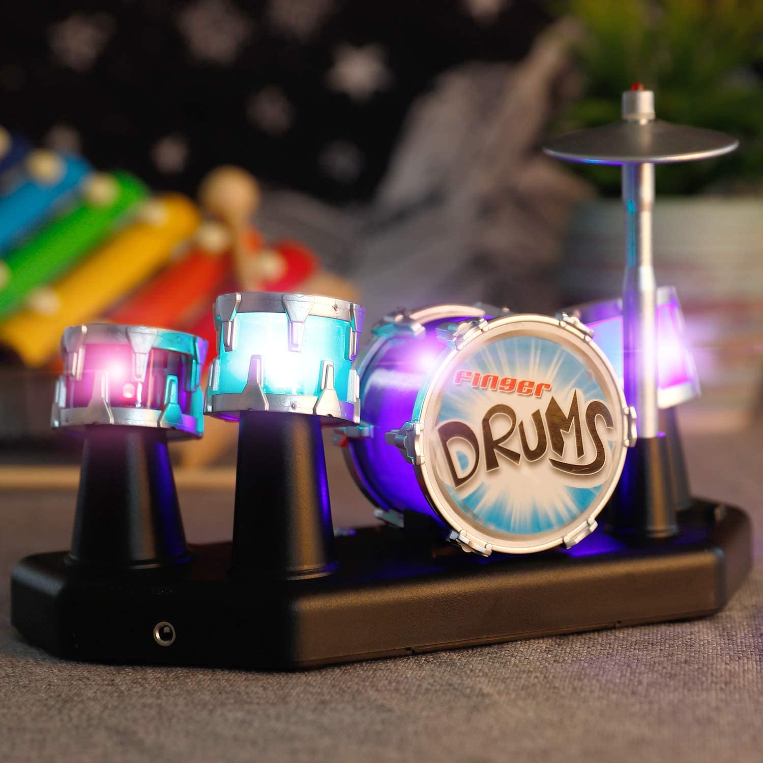 A mini desktop finger drum kit with purple and blue lights switched on.