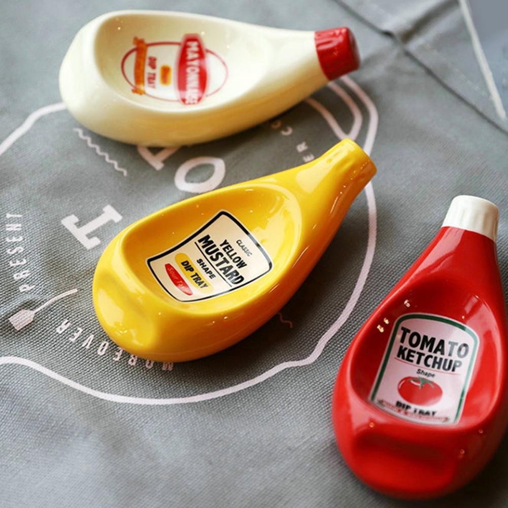 3 sauce dipping bowls which look like miniature versions of mayonnaise, ketchup and mustard which are used to hold dipping sauces for food.