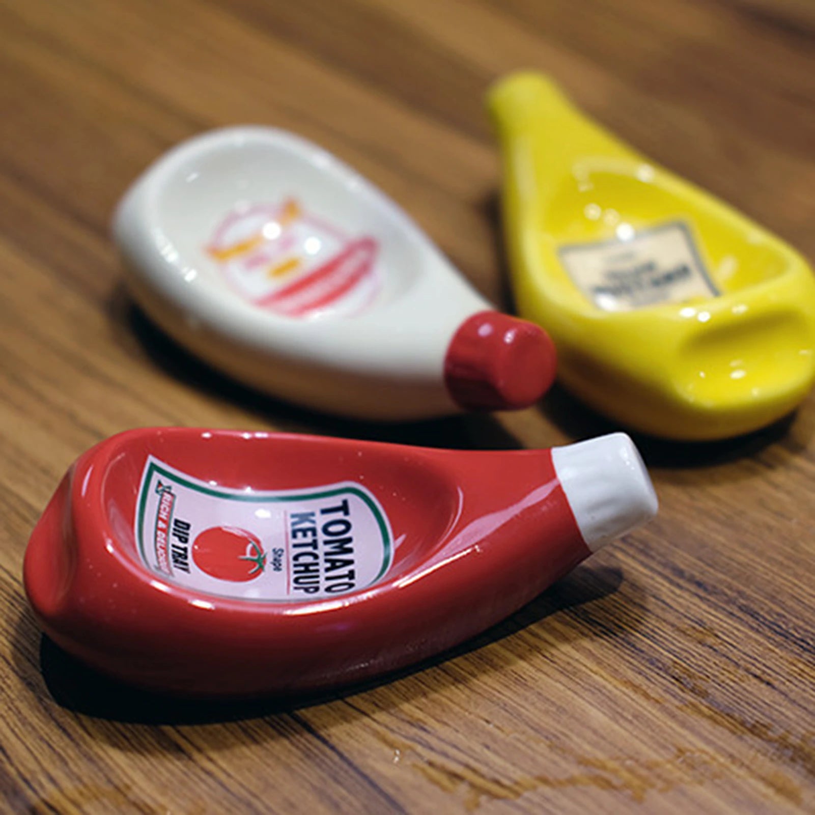 Three dipping bowls which looks like miniature versions of larger sauce bottles. These mini bowls are used to hold sauce for dipping.