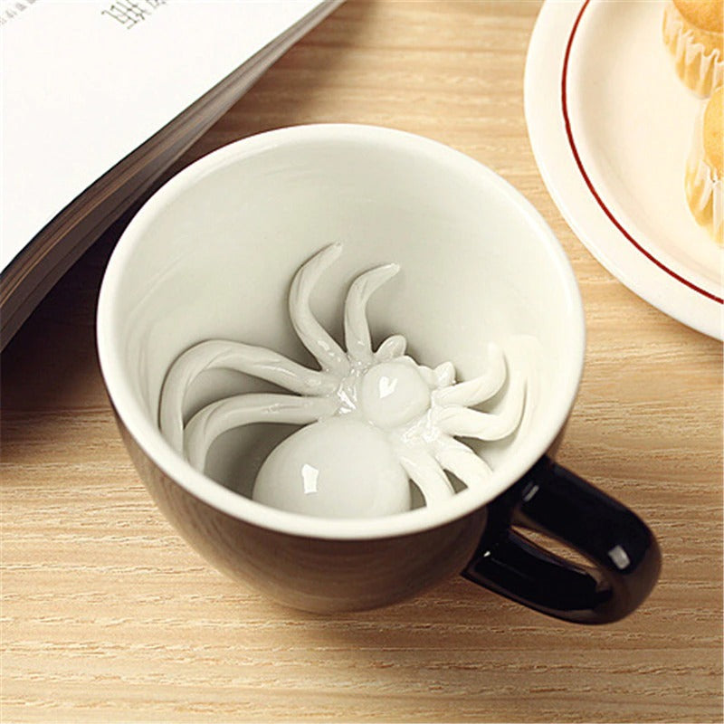 A black and white coffee cup which has a faux hidden spider at the base of it.