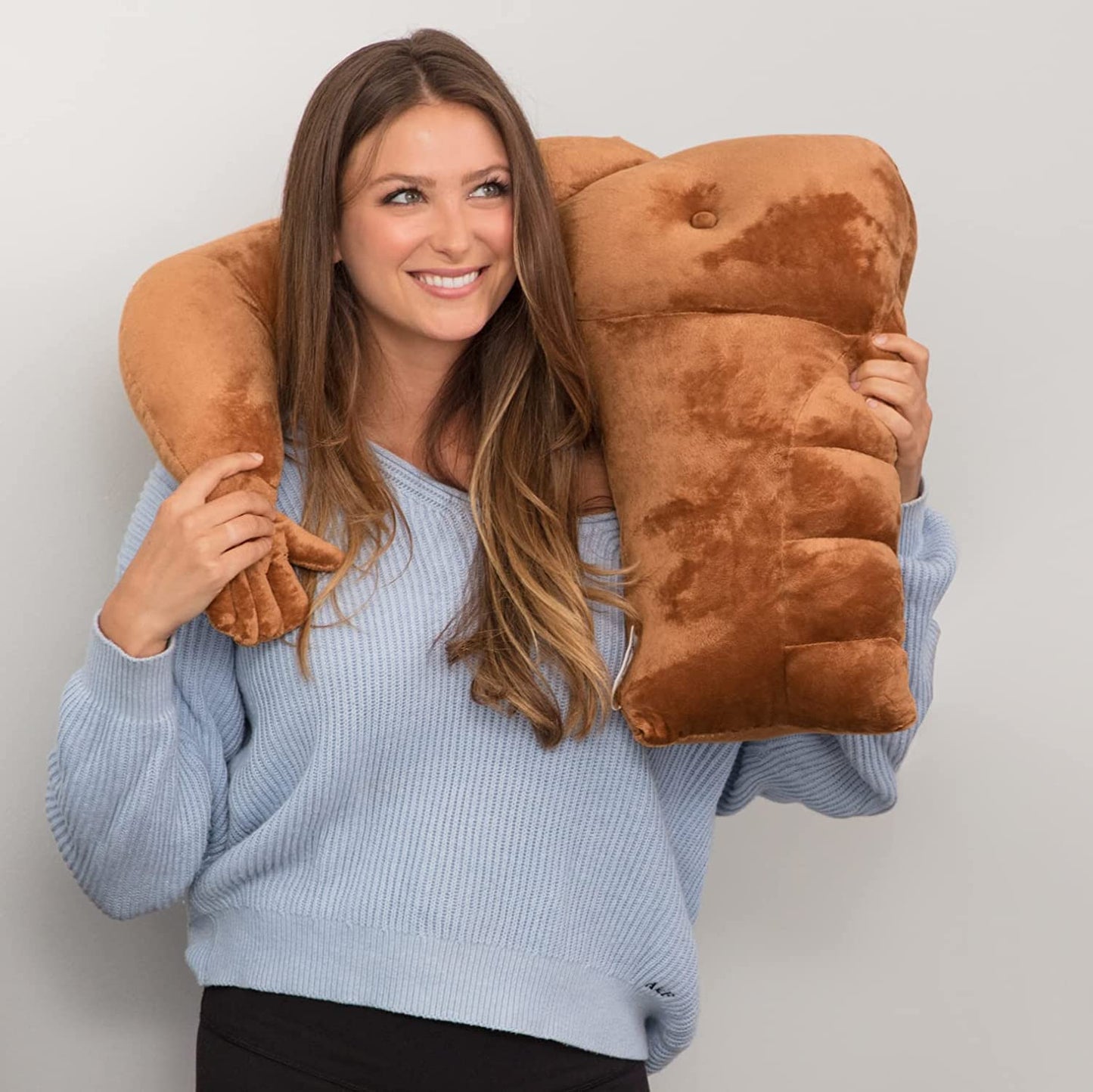 A woman has a muscle man pillow wrapped around her shoulders.
