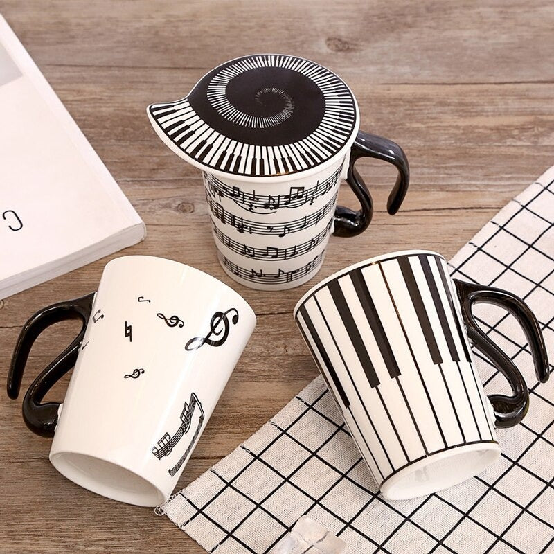 Three music mugs with lids which are all printed with music inspired images such as musical notes.