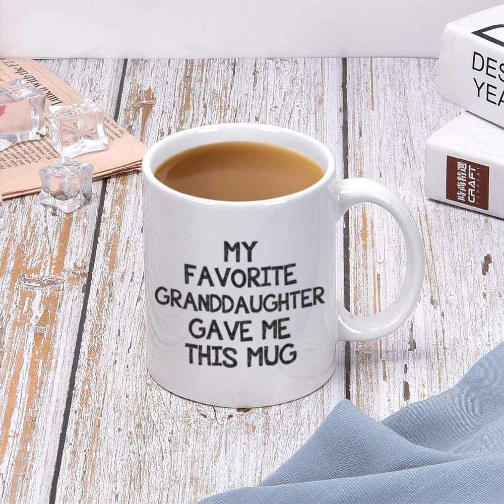 A coffee cup with words printed on it which say, 'my favorite granddaughter gave me this mug'. The coffee cup is on a wooden table.