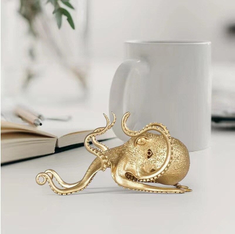 A golden colored octopus shaped mobile phone holder designed to hold phones.