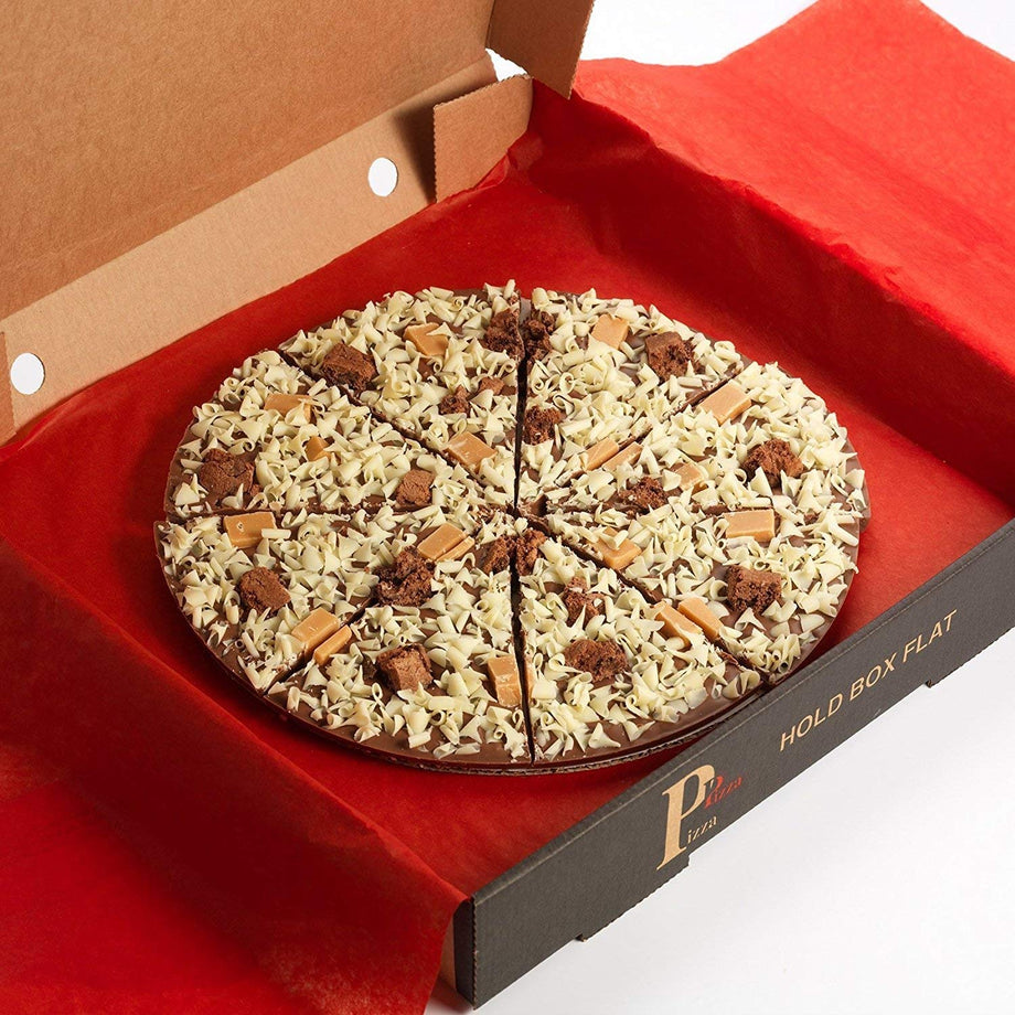 Round gourmet chocolate pizza topped with white chocolate shavings, brownie pieces and fudge in a pizza box
