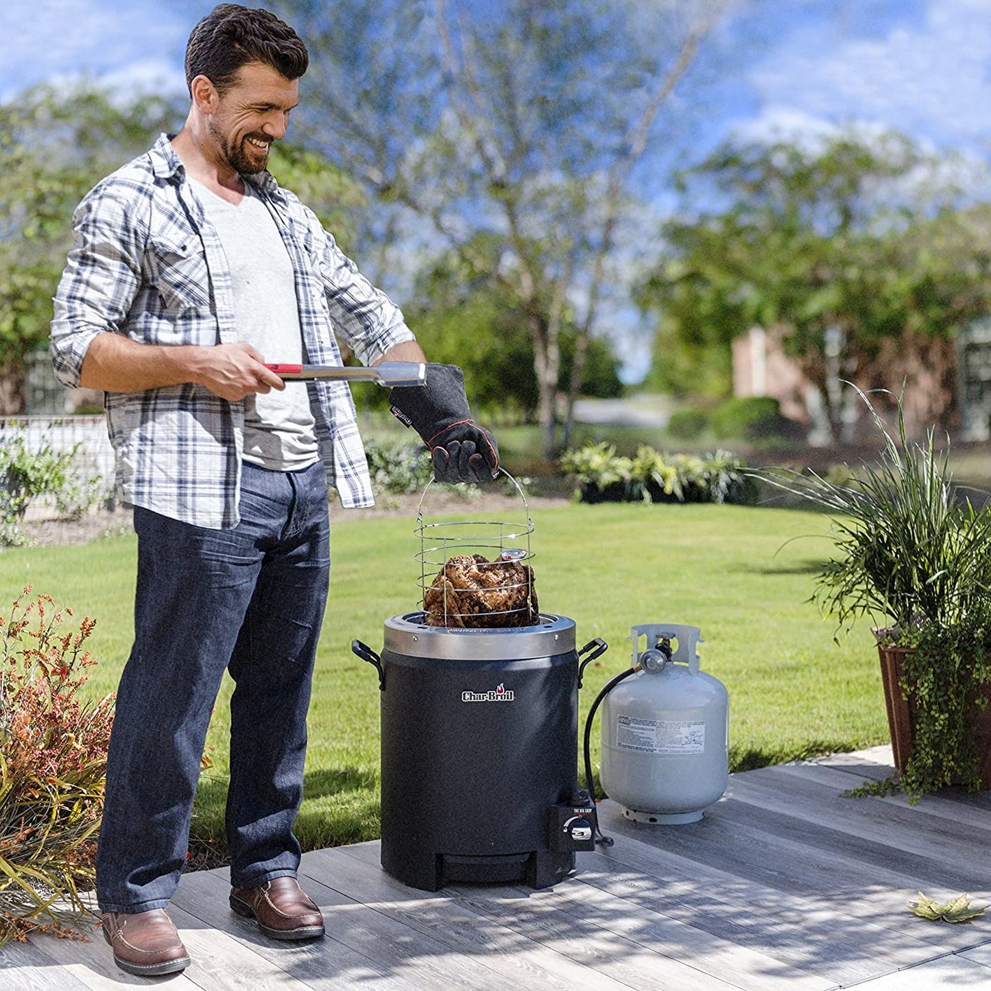 A man is outdoors placing a turkey into an oil-less liquid propane turkey fryer