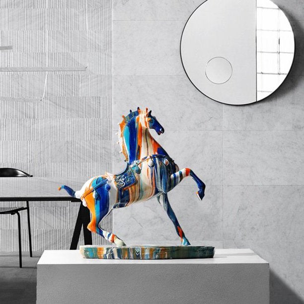 Horse figurine which appears to be covered in drips of colorful paint with a mirror and grey wall in the background.