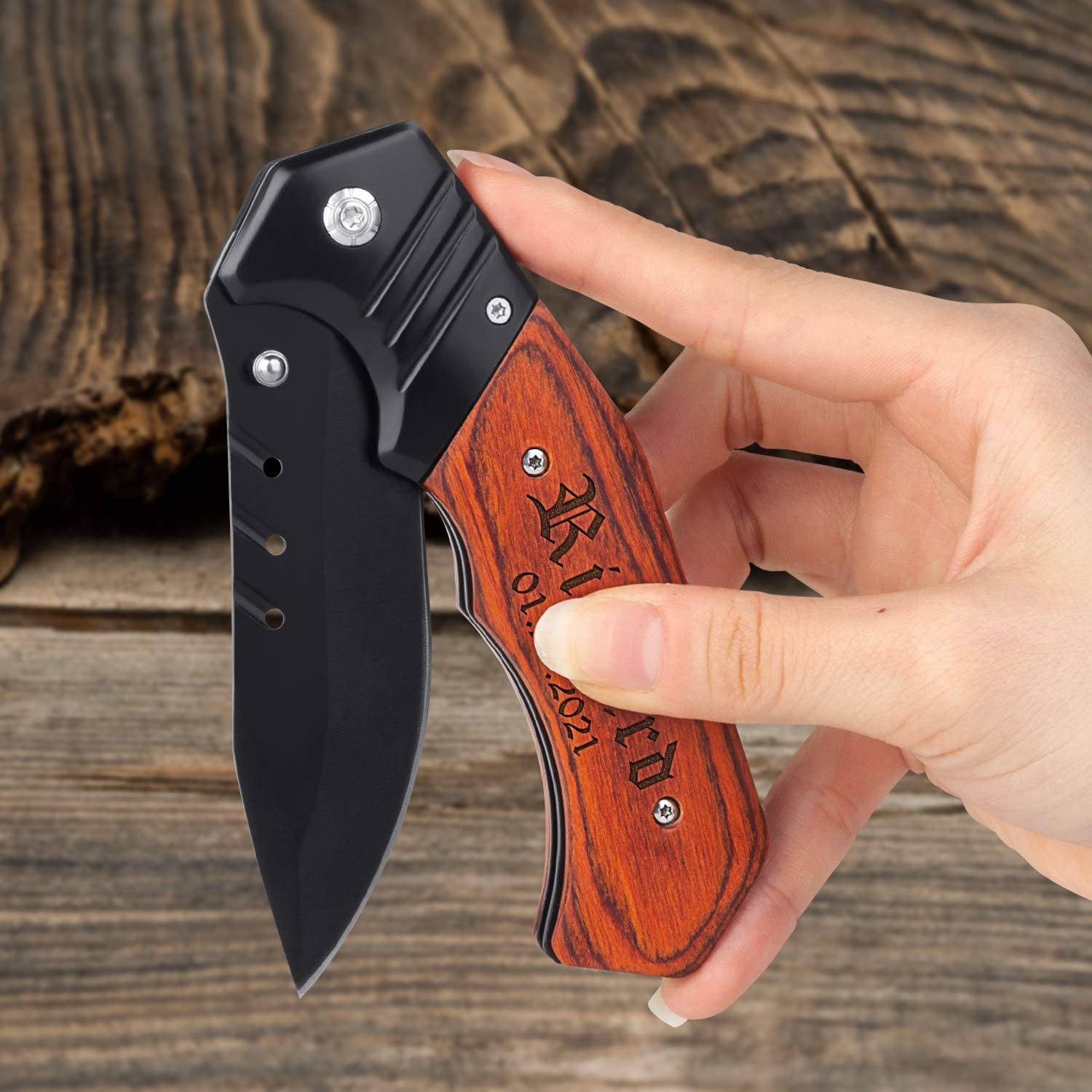 A hand holding a personalized engraved pocket knife with wooden handle half folded up.