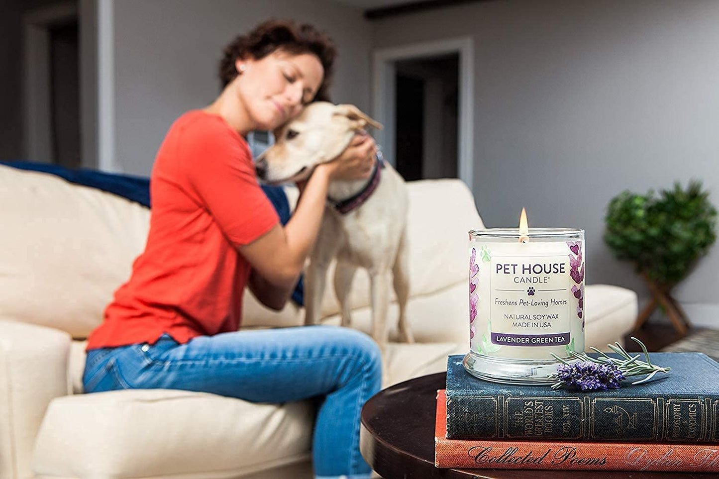 A woman cuddling her dog on a lounge with a pet odor eliminating candle in the foreground