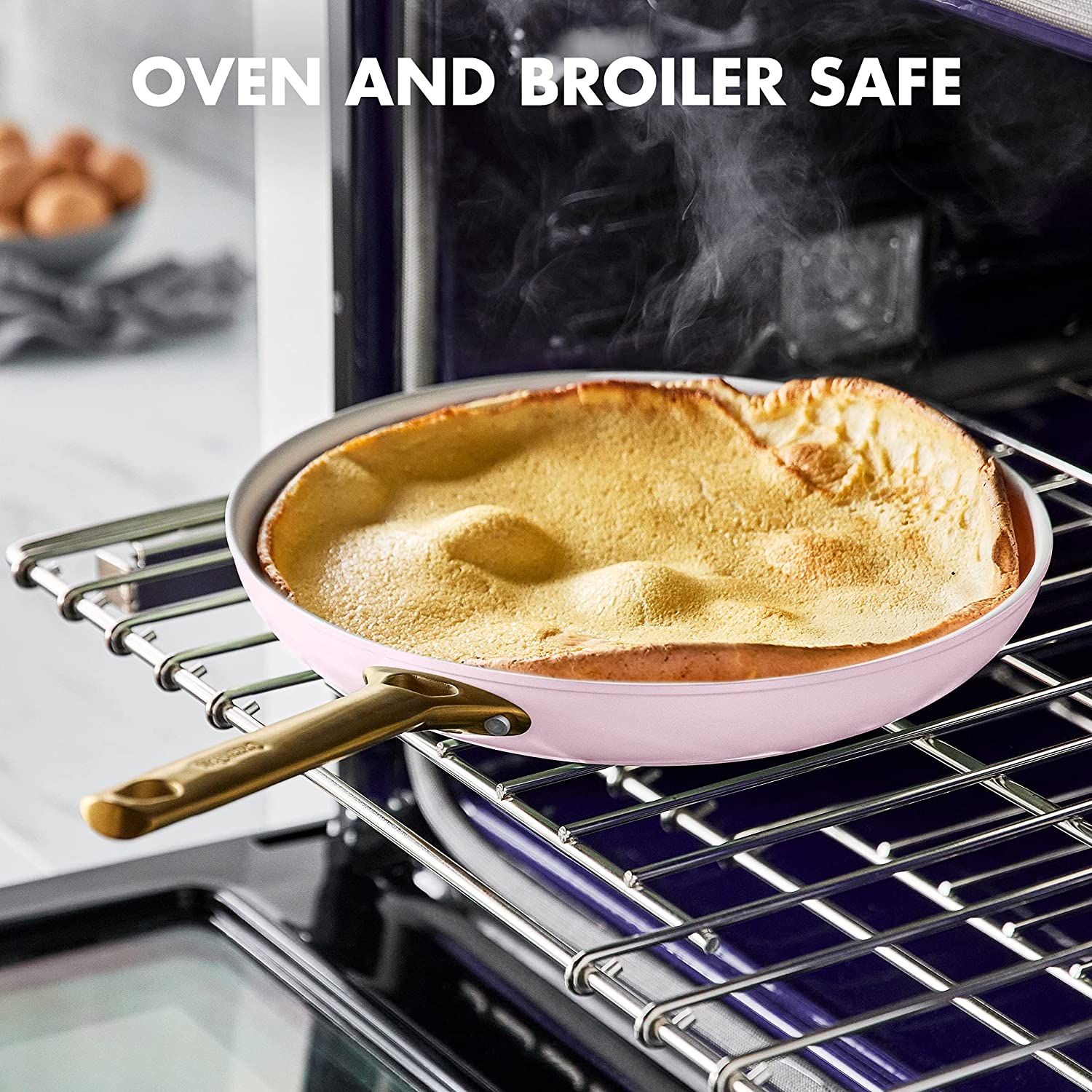 A pink frying pan is inside an oven with a pancake in it. The text says, 'Oven and broiler safe.'