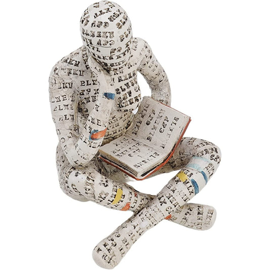 A sculpture of a woman with her legs crossed reading a book. It looks like her body is covered in book pages.