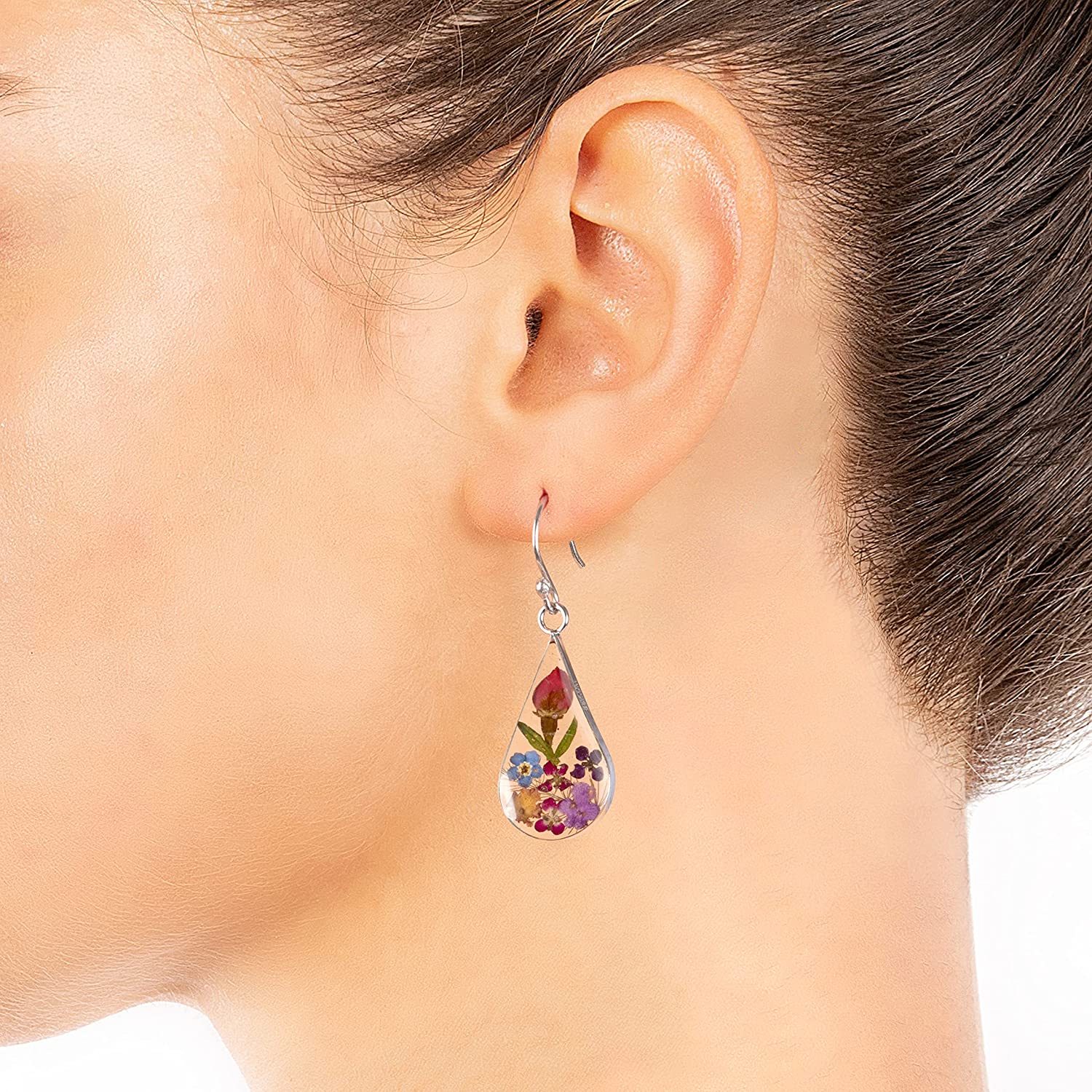 A woman is wearing an earring with real pressed flowers inside.