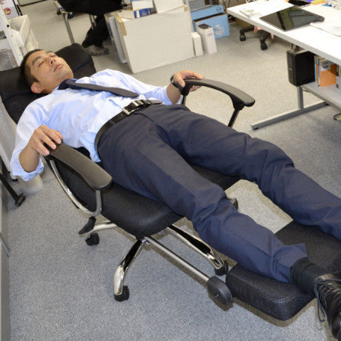 Office worker reclining in an extended office nap chair with foot support