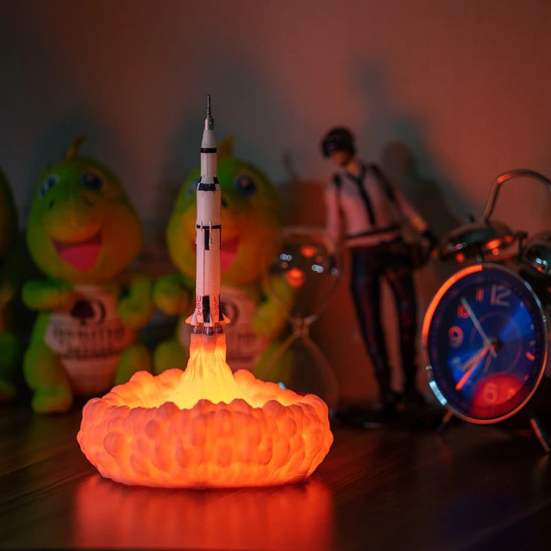 A rocket ship which is a night light. There is orange smoke at the back of the rocket ship which is a light.