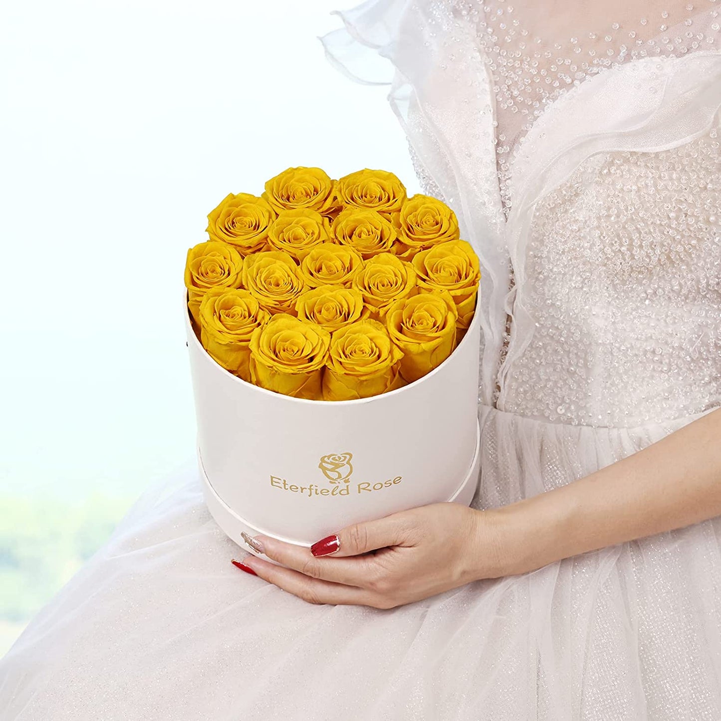 A woman is holding a box of yellow colored roses that last a year.