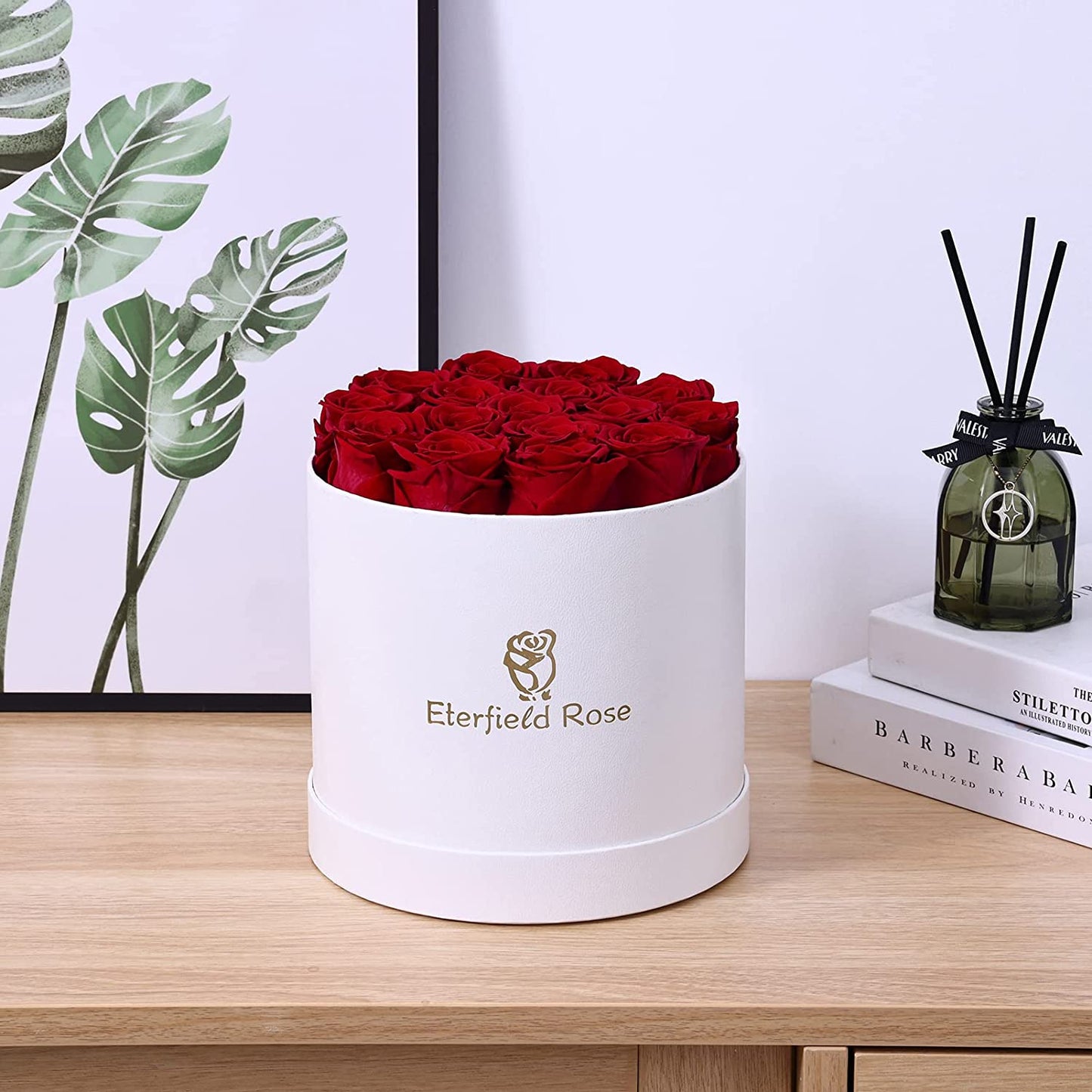A white box holding 16 red roses is on a wooden table.