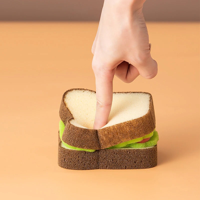 A sandwich which is actually a kitchen sponge. A finger is pressing down on the middle of the sandwich to show it is a sponge.