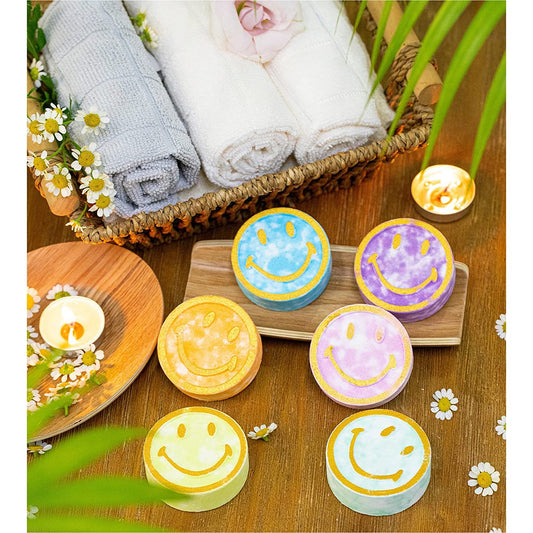 Six colorful shower steamers with smiley faces on them. There are also some hand towels and a tea-light candle.